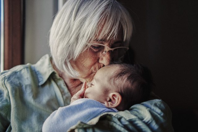 Close up portrait of a grandmother kissing the head of her newborn grandchild